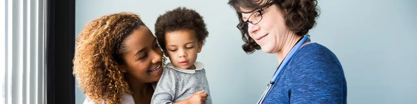 A doctor, patient and child in a clinical setting looking at a clipboard.