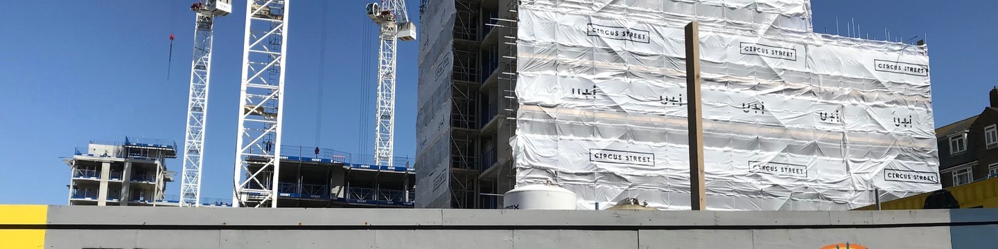 A building site with a development under construction, cranes, and hoardings.