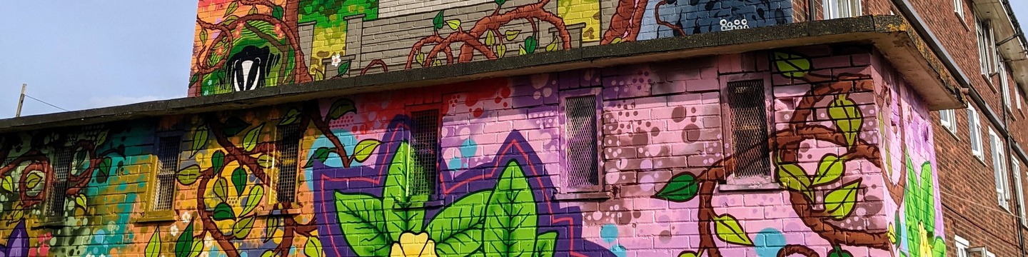 Colourful mural on side of building depicting trees and animals.