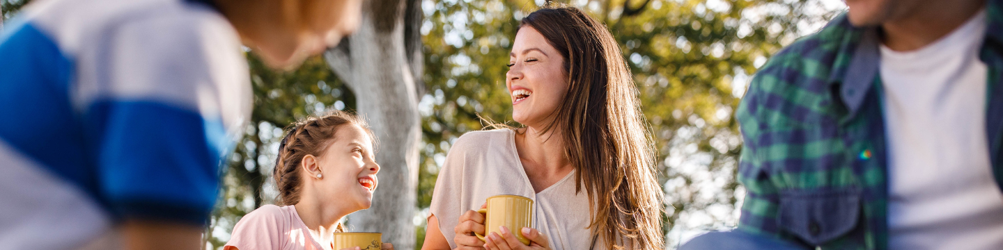 A mum and daughter at a community event, laughing towards one another.
