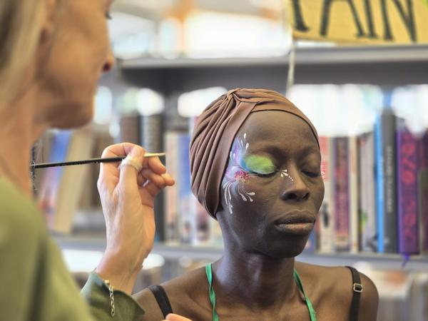 Woman getting her face painted with green swirls.