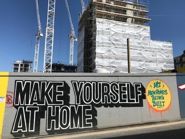 A building site with a development under construction, cranes, and hoardings.